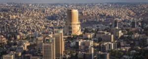 Aerial cityscape with a prominent cylindrical tower rising among dense buildings.