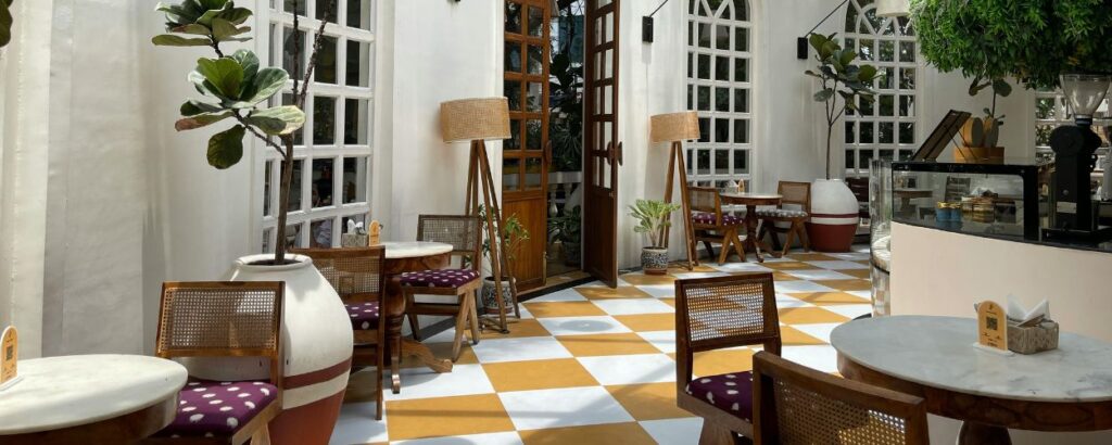 Cafe seating area with orange-and-white checkered floor, wooden chairs with purple cushions, and marble tables