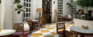 Cafe seating area with orange-and-white checkered floor, wooden chairs with purple cushions, and marble tables
