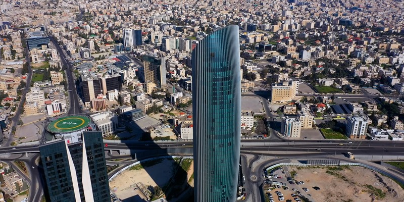 Aerial cityscape with a prominent cylindrical tower rising among dense buildings.