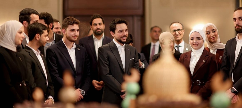 Group of professionals in suits and hijabs at a formal gathering, surrounding a ceremonial display with a large golden dome.
