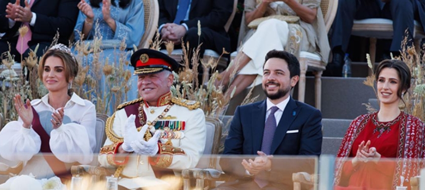 Dignitaries at a formal ceremony: a decorated military officer sits center with a suited man and two women on either side.
