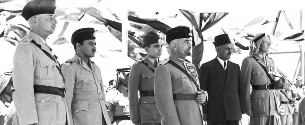 Group of uniformed men and a civilian in a suit standing in a line during a parade (black-and-white photo).