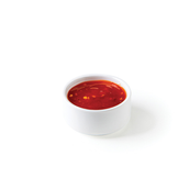 Small white cup filled with red tomato sauce on a white background.