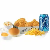 Plate of fried chicken pieces with french fries, small sauce cups, and a blue can of soft drink.